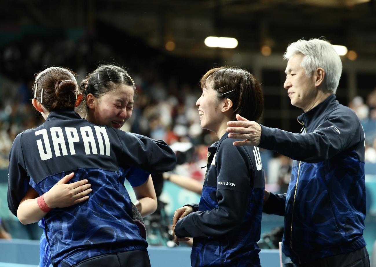 女子団体準決勝　ドイツに勝利し決勝進出を決めたシングルス3の張本（左から2人目）は、涙を流しながらベンチに戻り、早田（左）平野（中央）渡辺監督に笑顔で迎えられる（撮影・河田真司）