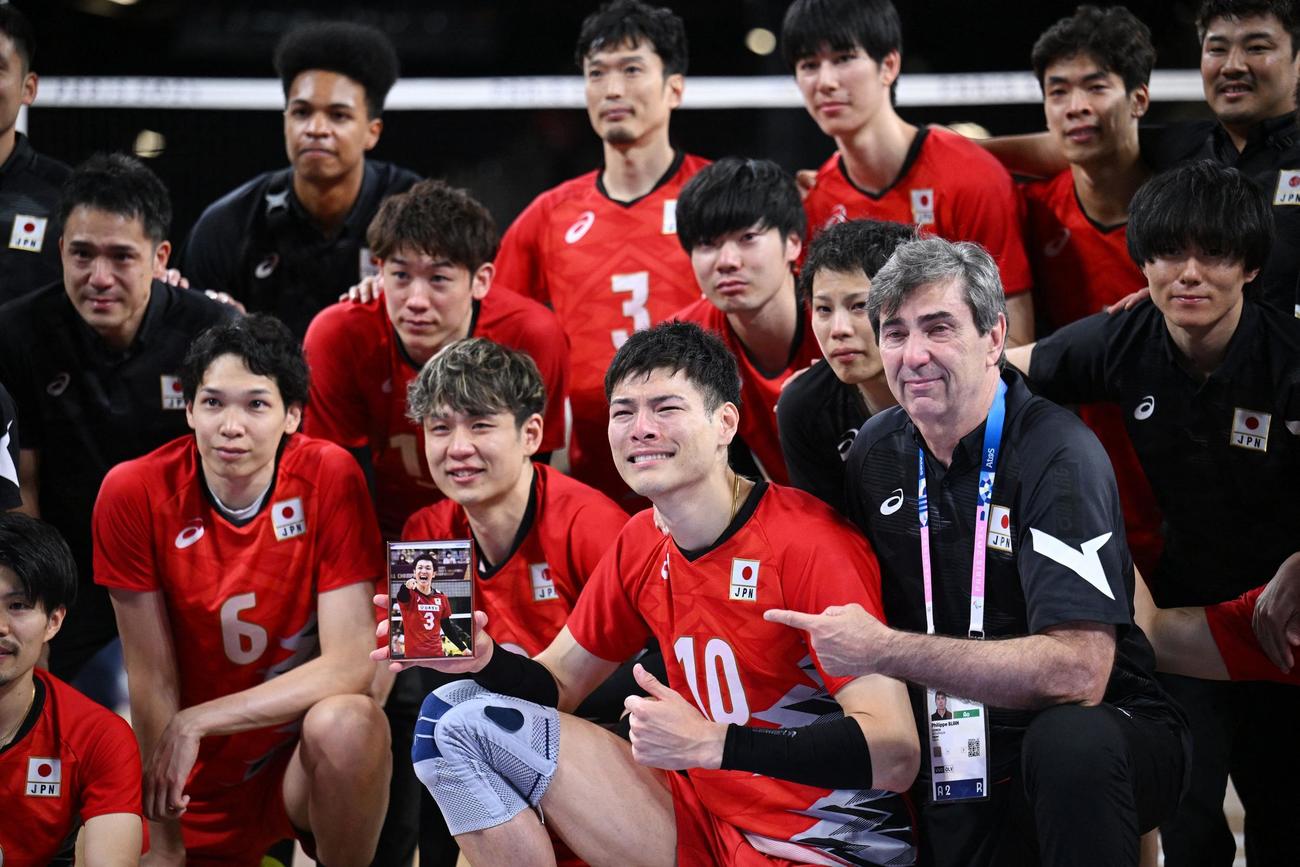故藤井直伸さんの写真とともに、集合写真を撮る日本代表の選手たちと、ブラン監督（ロイター）