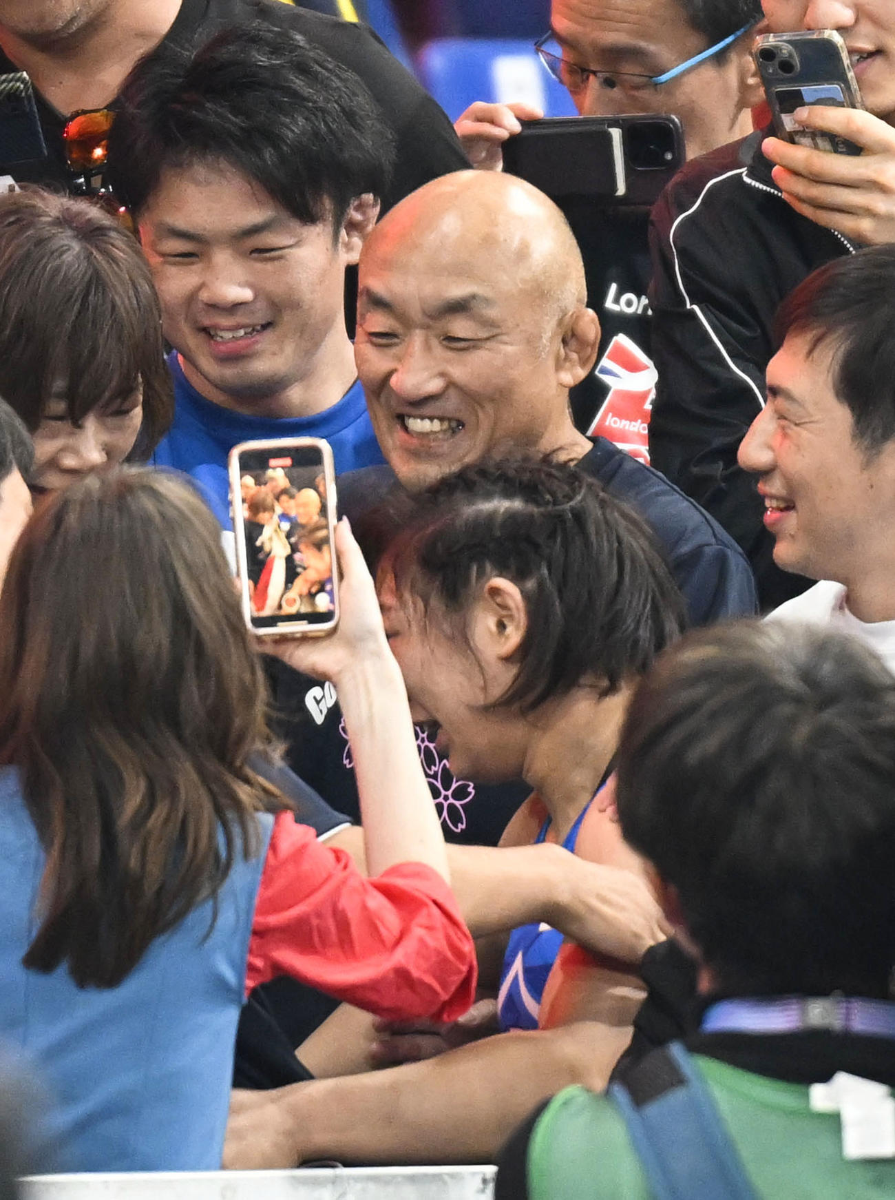 女子62 キロ 級で優勝した元木咲良（下）を迎え、笑顔の父康年さん（中央）（共同）