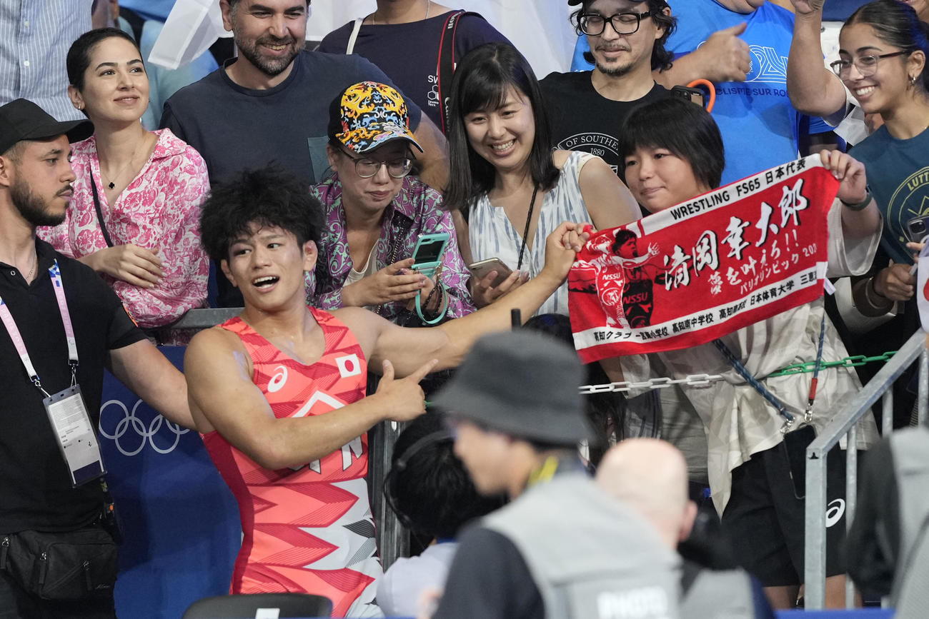 レスリング男子フリースタイル65kgで金メダルを獲得した清岡幸大郎は観客席へ向かい、幼なじみで女子57キロ級を制した桜井つぐみ（右横）と喜びを分かちあう