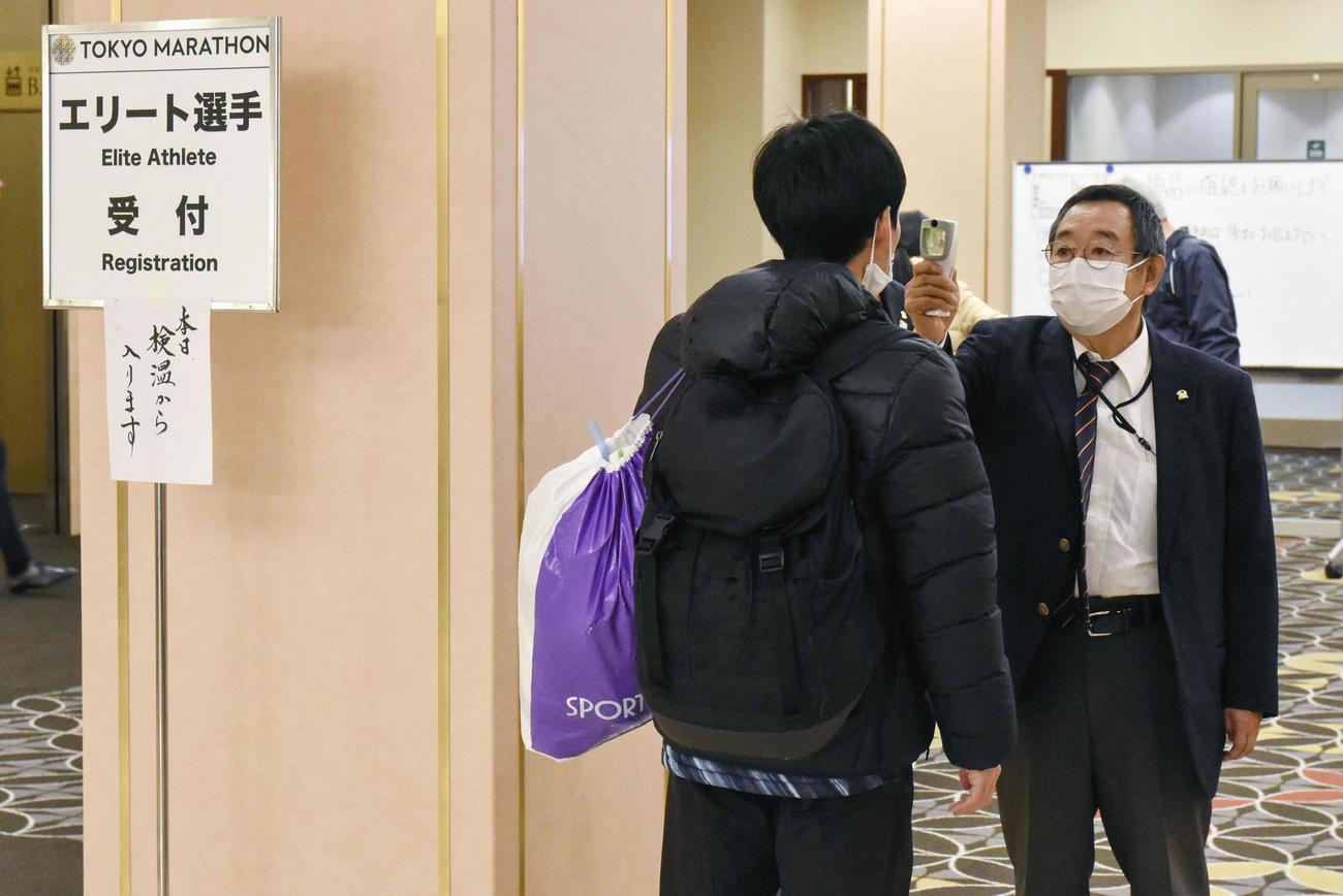 受け付け前に東京マラソンの大会関係者（右）に体温を測定される選手（共同）