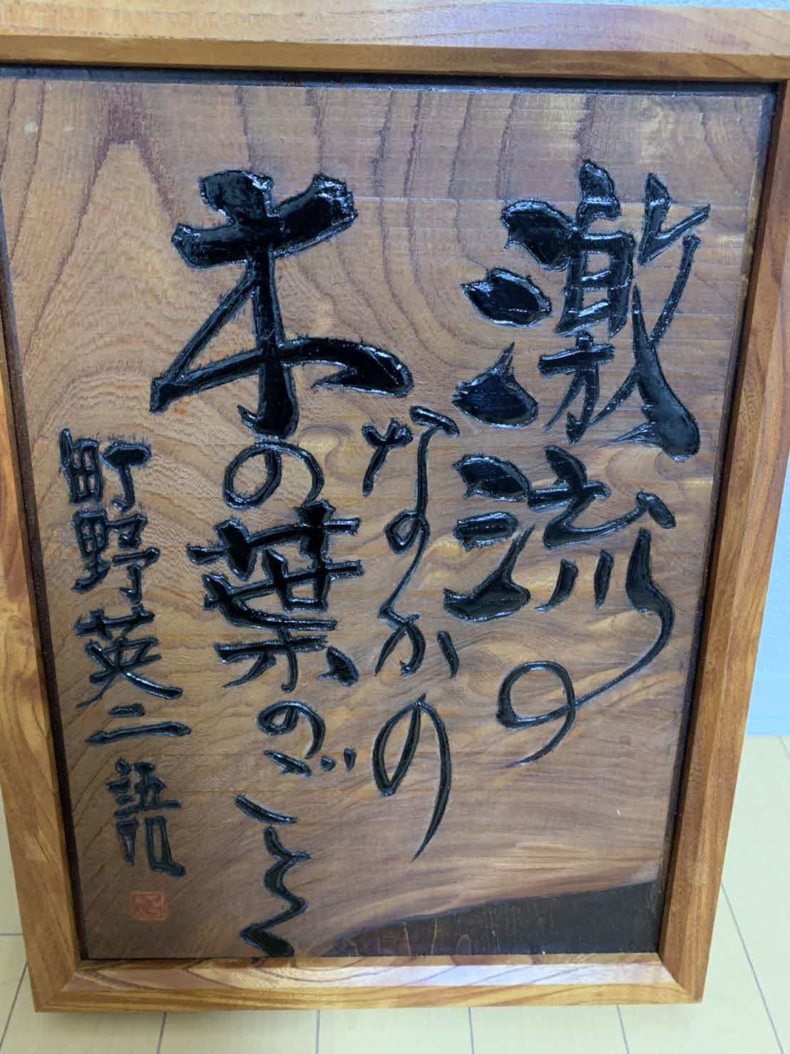 中村が玄関に飾る町野英二さんの言葉が刻まれた木彫りのレリーフ（富士通提供）