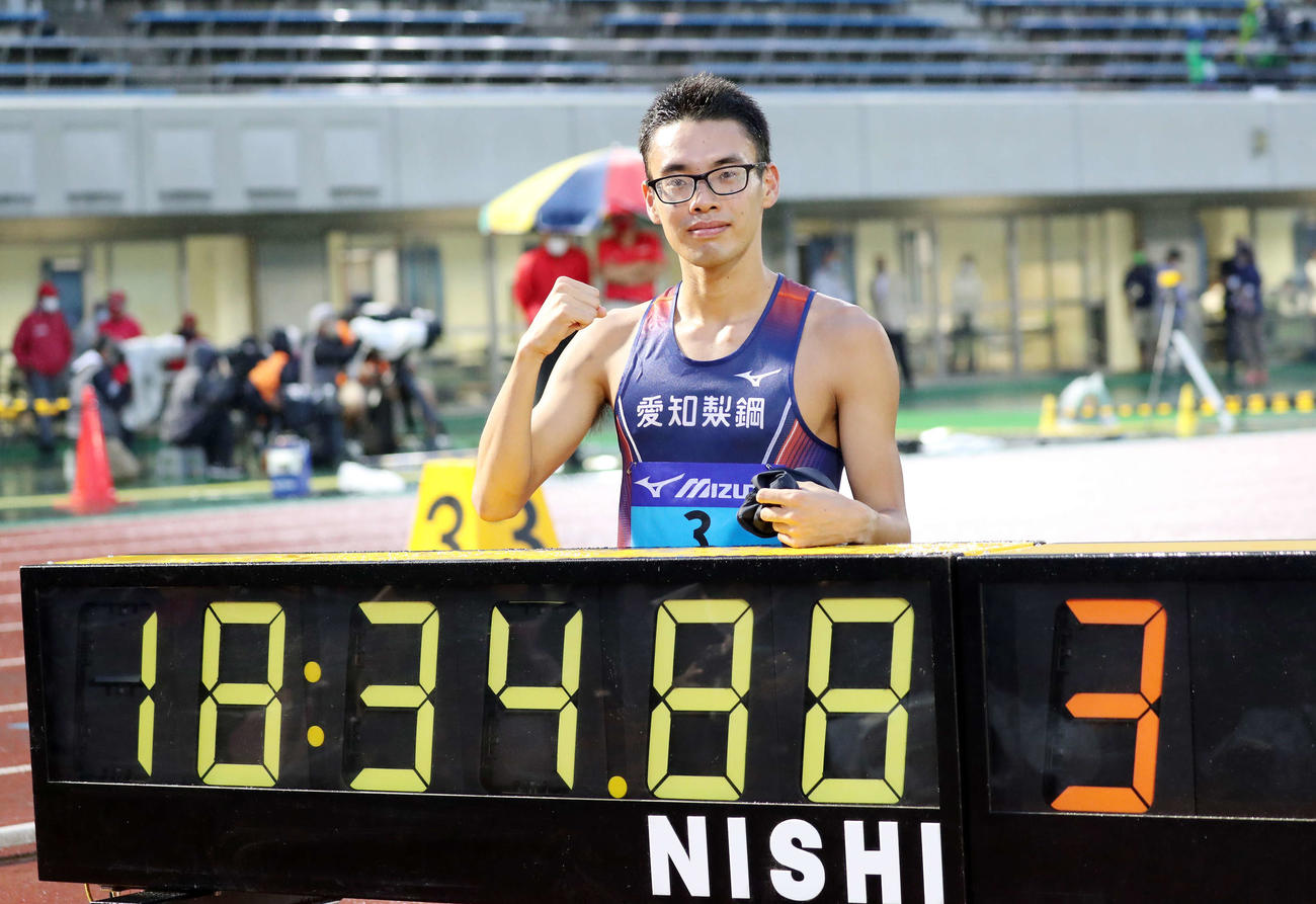 男子5000メートル競歩で日本新記録を出し時計の前でガッツポーズする山西（撮影・鈴木正人）