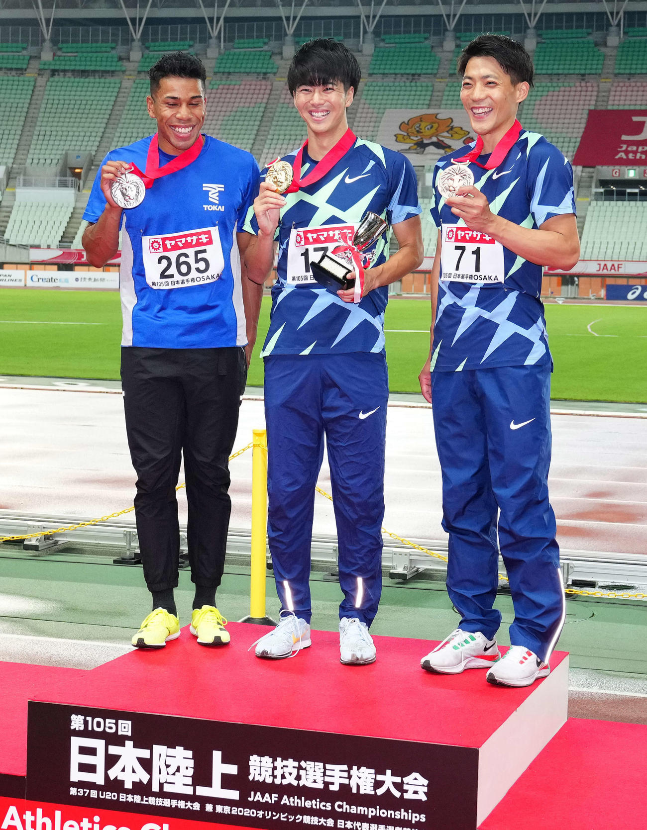 男子100メートルの表彰台に上がり笑顔を見せる、左から2位のデーデー、優勝の多田、3位の山県（撮影・江口和貴）