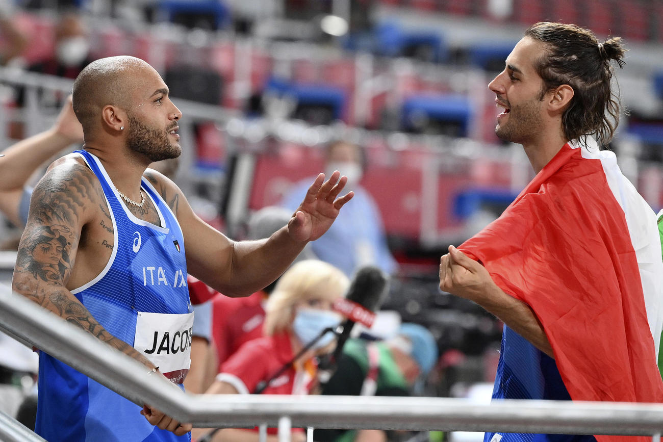 1日、男子100メートルを制したヤコブス（左）は男子走り高跳びで金メダルを獲得したタンベリの祝福を受ける（AP）