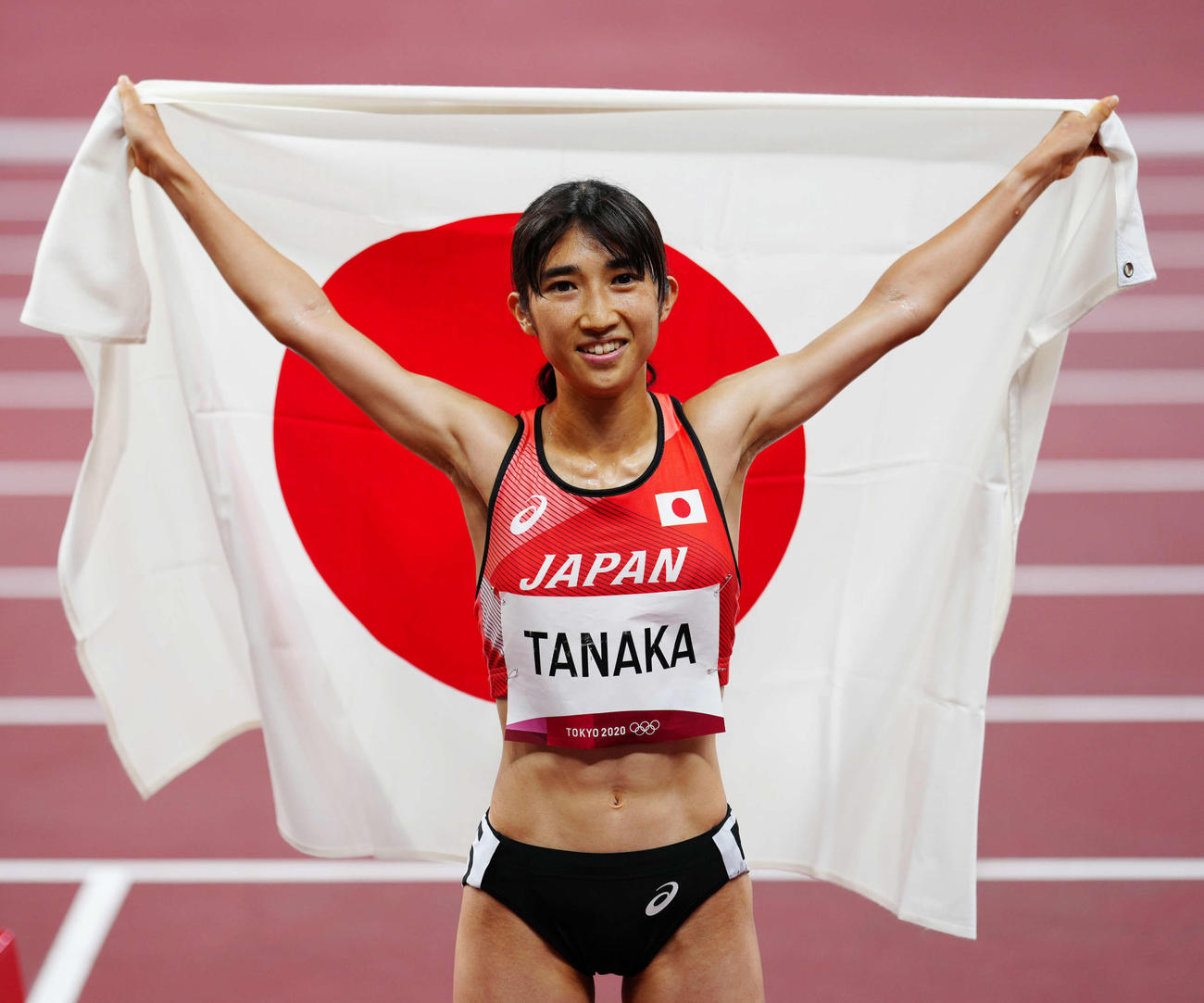 女子1500メートル決勝、8位入賞で日の丸を背に広げる田中（撮影・江口和貴）
