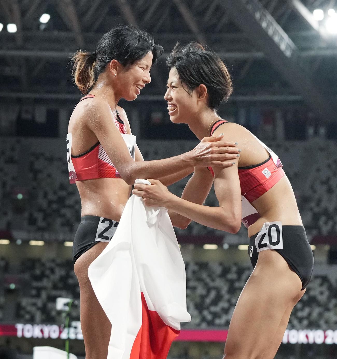 女子1万メートルで7位入賞を果たし新谷（左）と健闘をたたえ合う広中（共同）