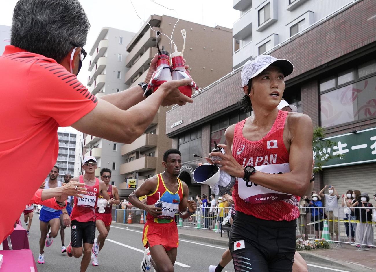 男子マラソン　16 キロ 付近の給水所で、ドリンクを受け取った大迫傑（右）（共同）
