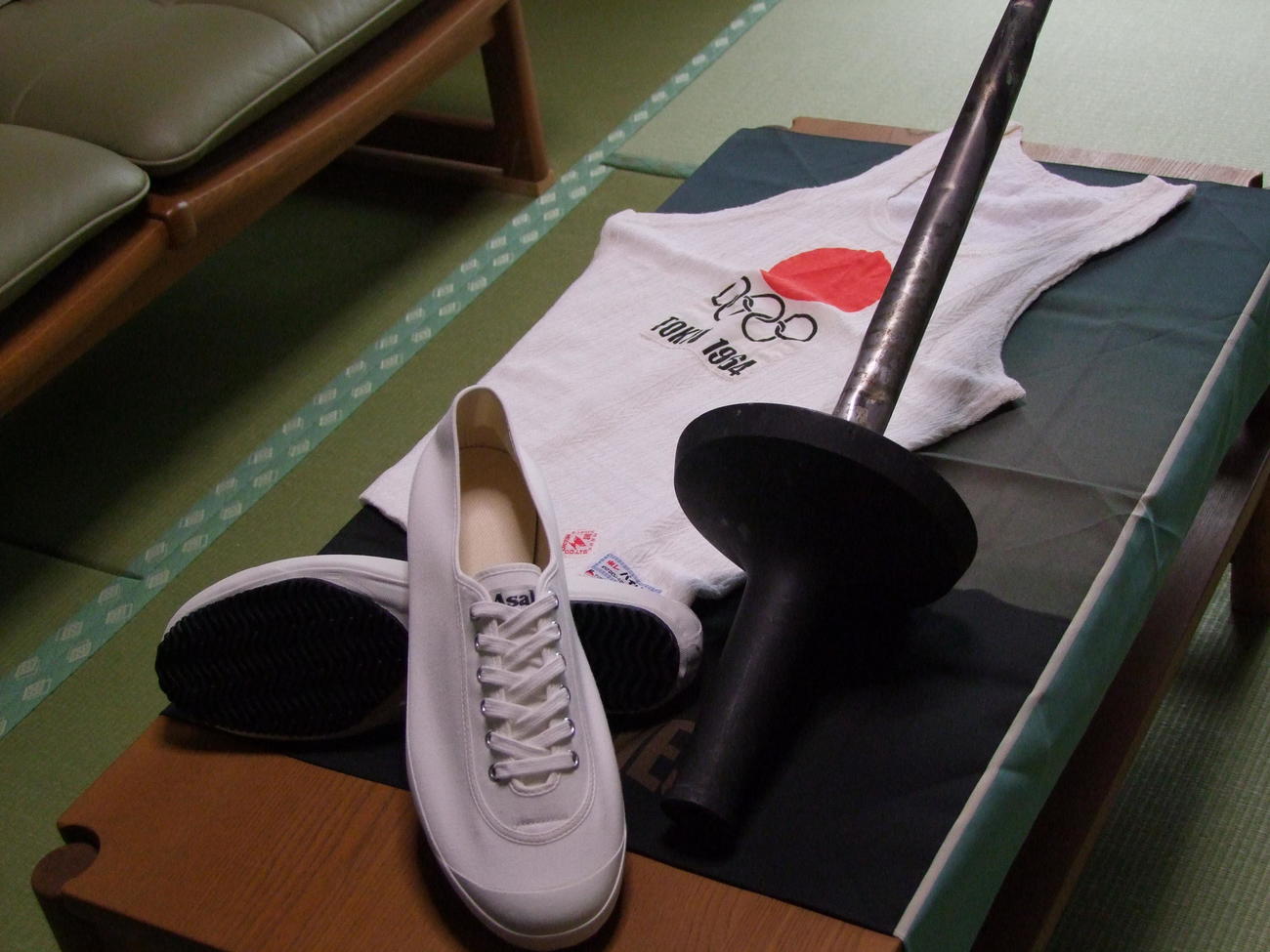 宮城勇さんにプレゼントされた当時、届かなかった64年東京五輪聖火ランナーシューズの復刻版（手前）。ユニホームとトーチは64年東京五輪で聖火ランナーを務めた際に使用したもの