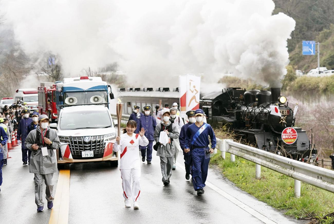 真岡鉄道のSLと並走する聖火ランナー（手前中央）＝28日午後、栃木県茂木町（代表撮影）