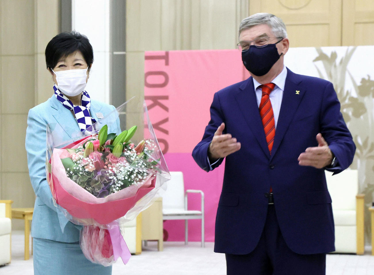 IOCのバッハ会長（右）から誕生日の花束を贈られ、笑顔を見せる東京都の小池百合子知事（共同）