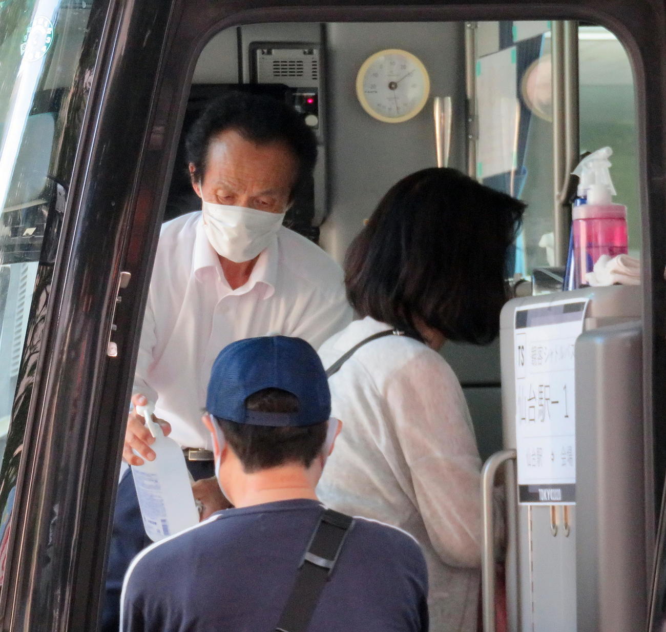 シャトルバスで乗客たちに消毒を行うバス運転士（撮影・鎌田直秀）