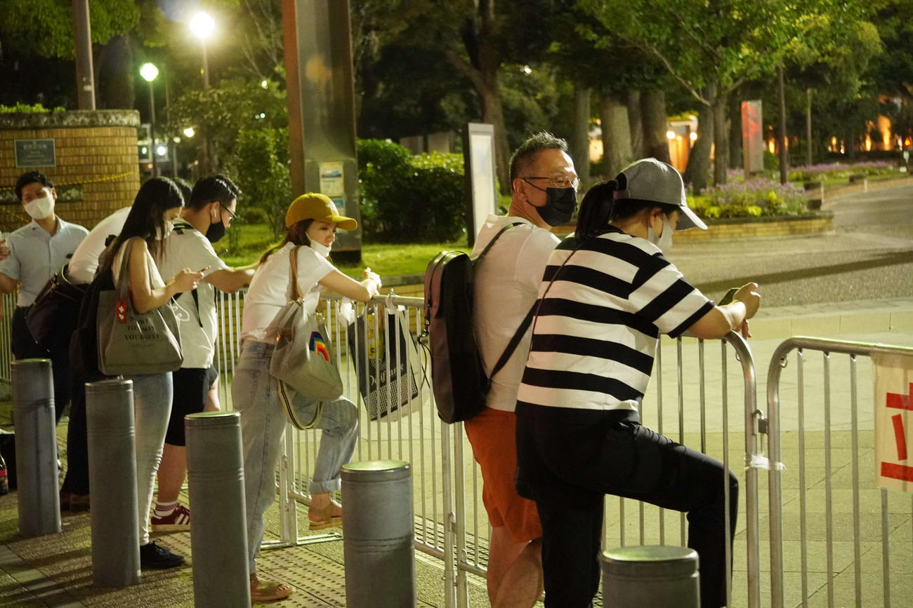 ソフトボール決勝を会場のゲート前で観戦する人々（撮影・沢田直人）