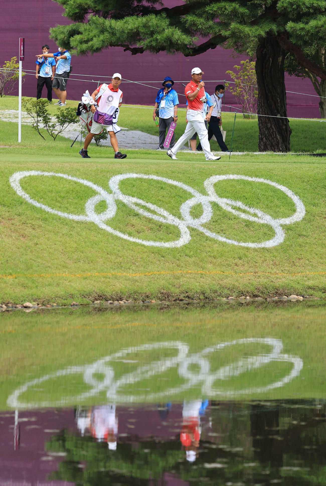 男子ゴルフ初日、10番、五輪マークを横目にグリーンに向かう松山（右）（撮影・河野匠）