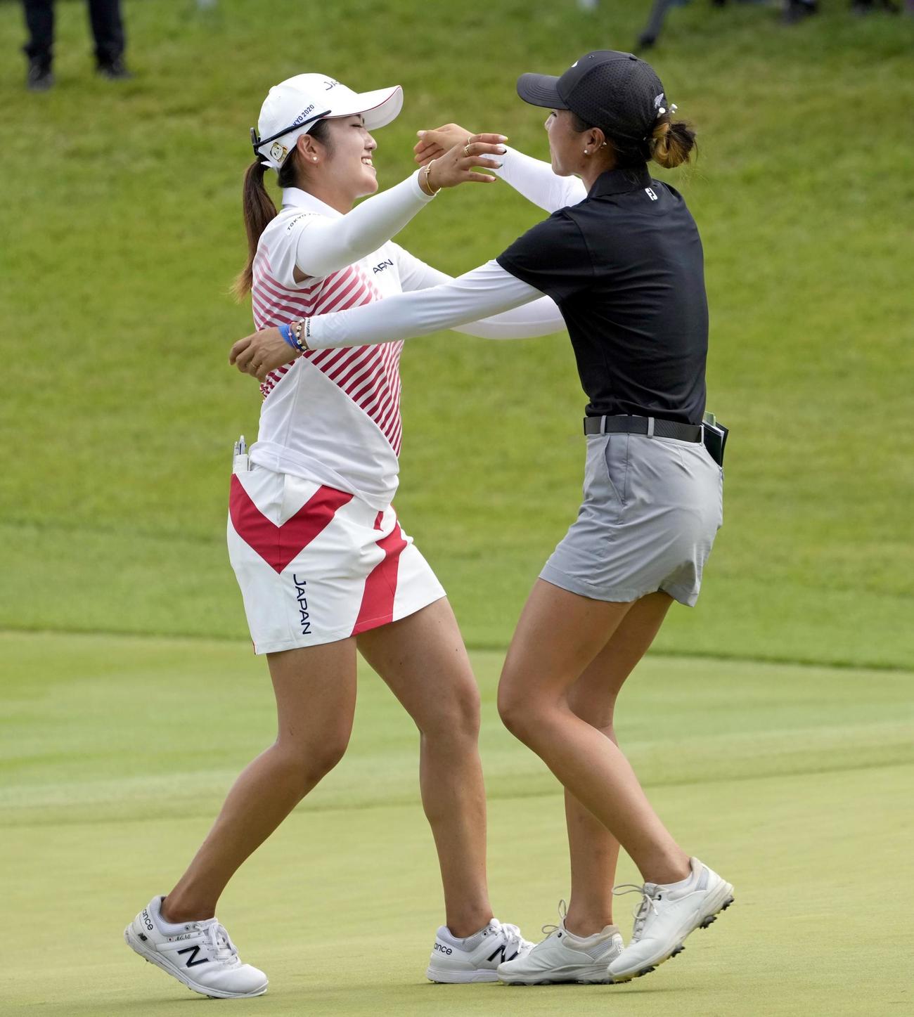 女子ゴルフの銀メダルを懸けたプレーオフを制し、リディア・コ（右）と健闘をたたえ合う稲見萌寧（共同）