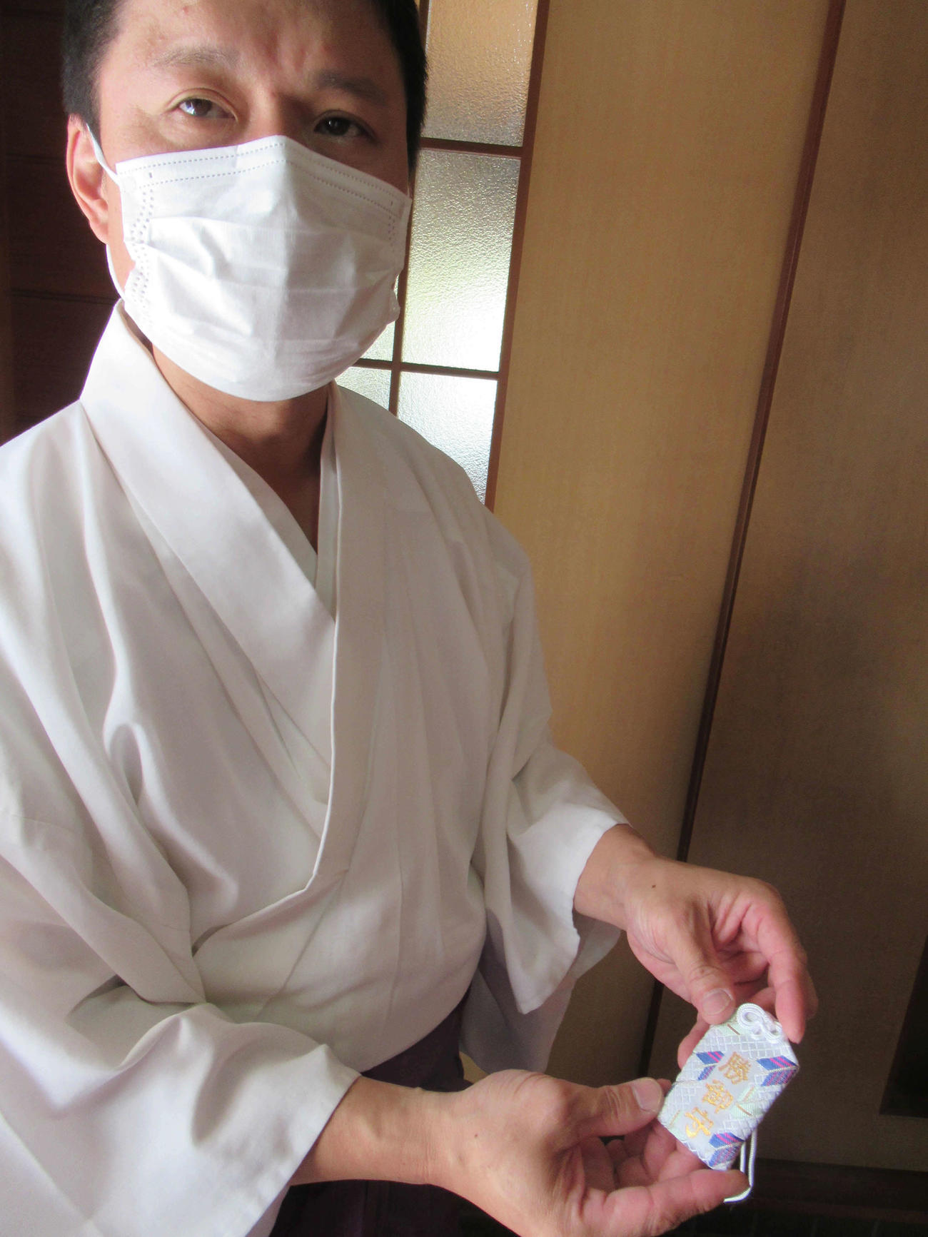 阿部詩に授けた「勝ち運お守り」を手にする三石神社の禰宜（ねぎ）小林さん（提供＝三石神社）