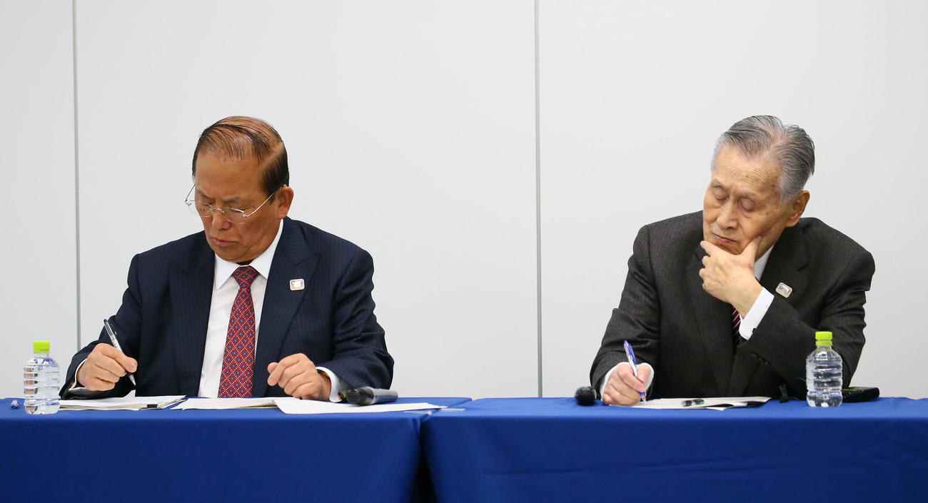 会見中、メモを取る東京五輪・パラリンピック大会組織委員会の森会長（右）と武藤事務総長（撮影・足立雅史）