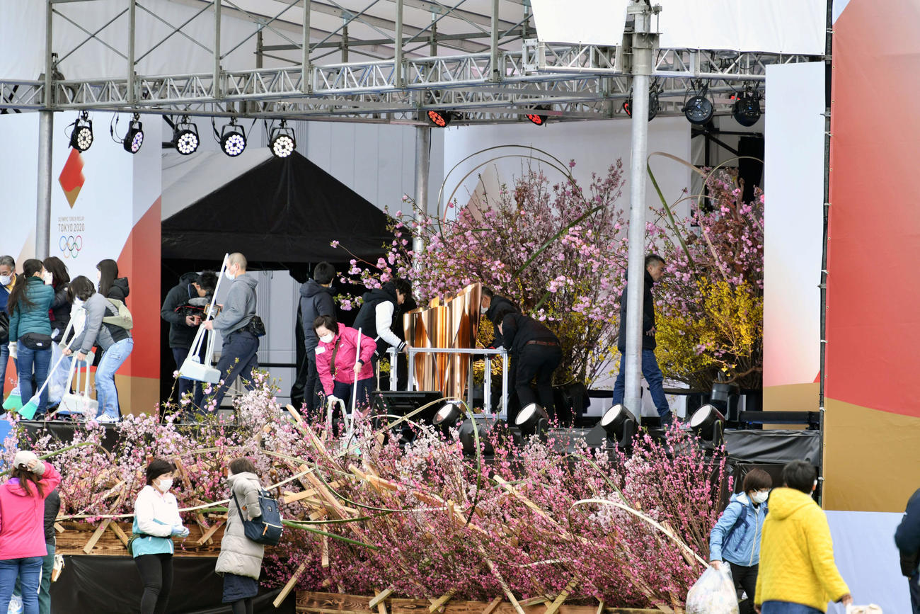 聖火リレー中止が発表されて一夜明け、花で飾られたグランドスタートのステージに聖火皿を設置する関係者ら（撮影・滝沢徹郎）