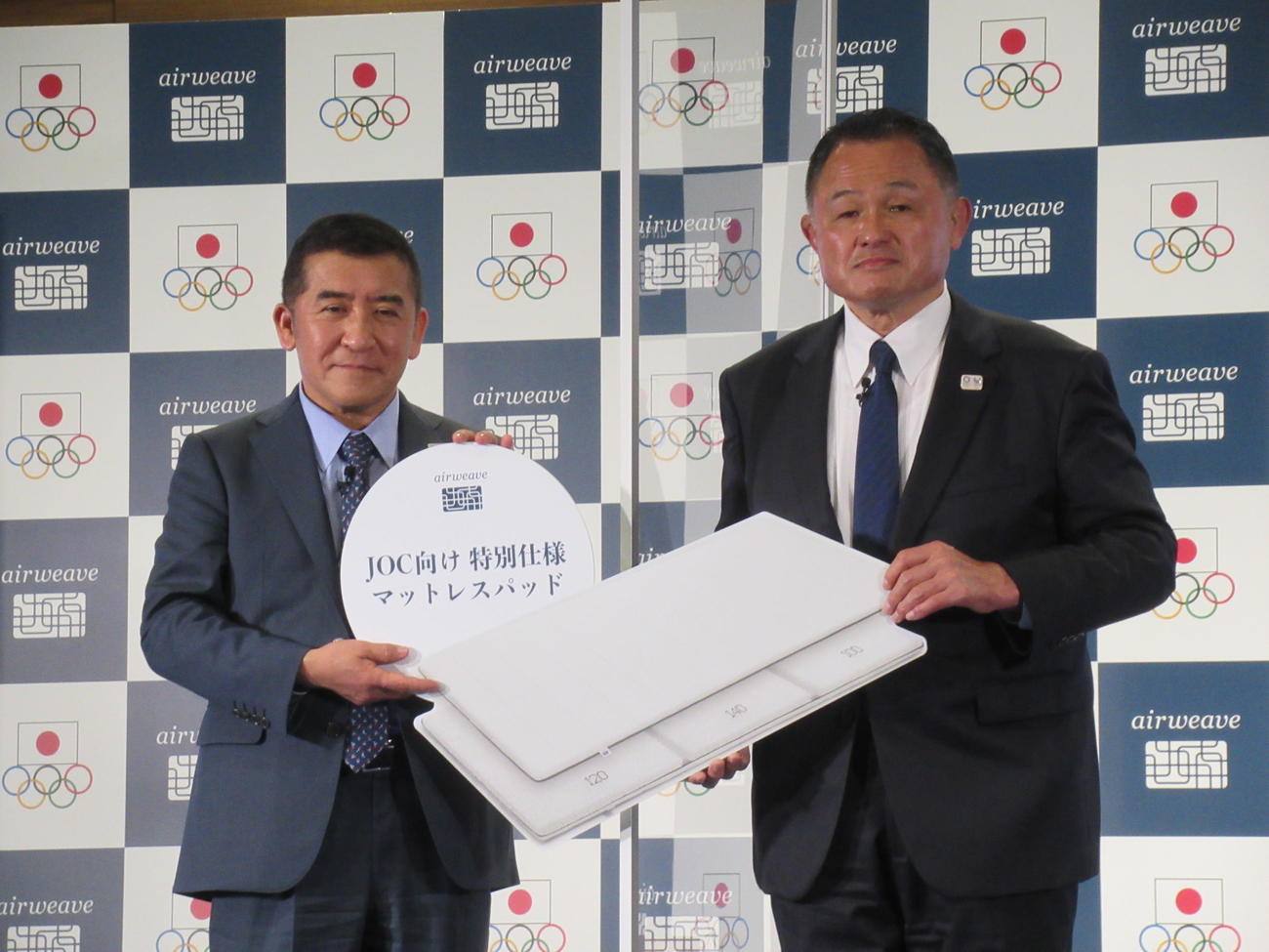 寝具メーカーのエアウィーブ社からマットレスパッド600床分を寄贈されたJOC山下泰裕会長（右）。左は同社の高岡本州社長（撮影・益田一弘）