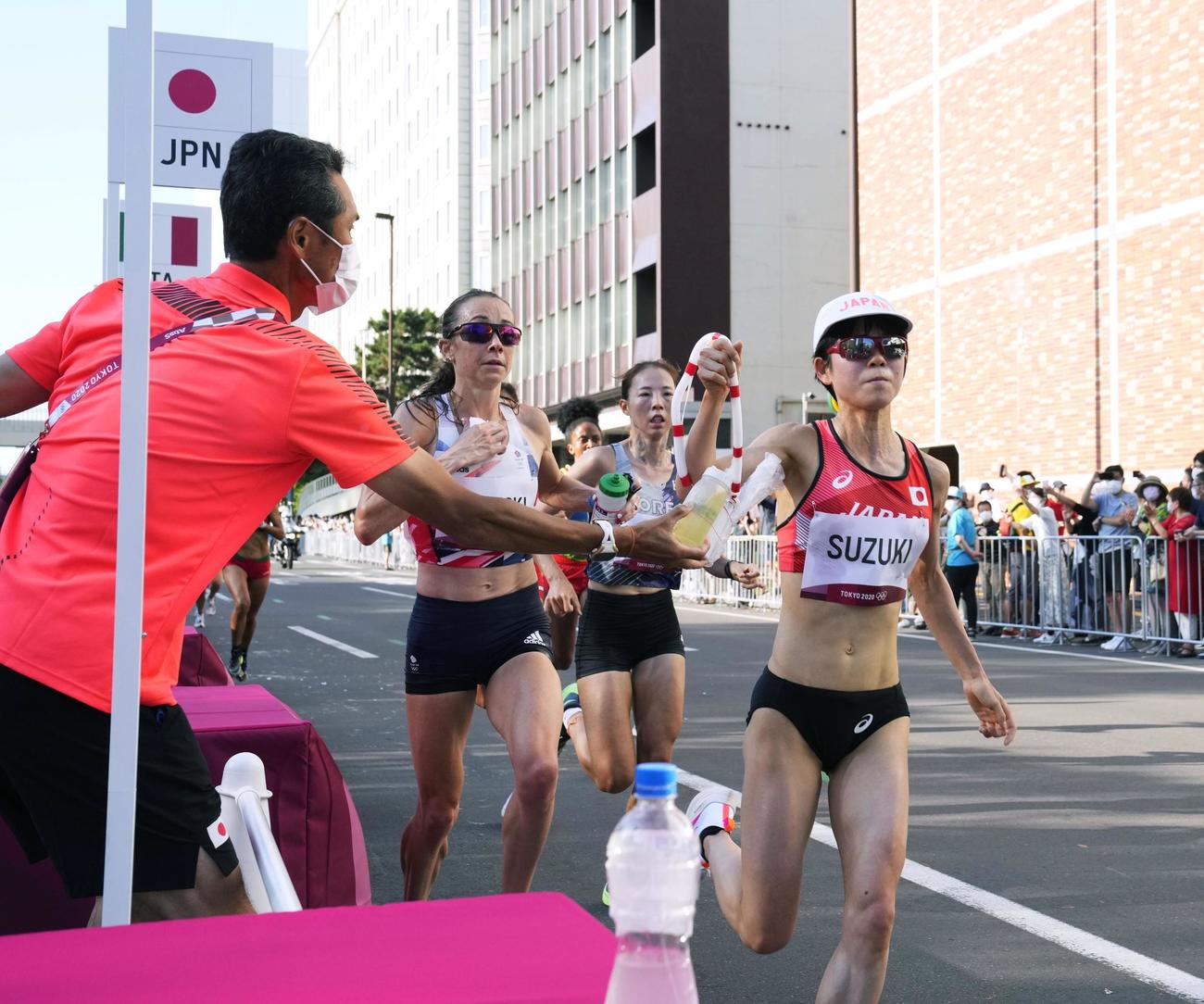 13キロ付近の給水所で、ドリンクを取る鈴木亜由子（右）（共同）