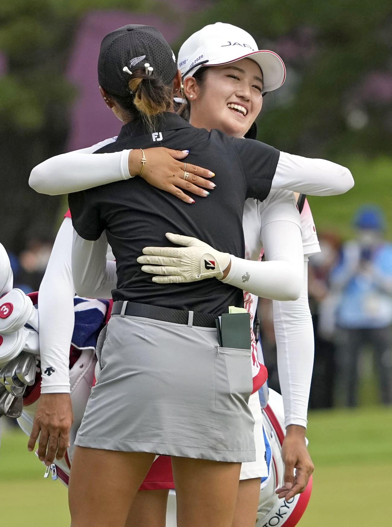 女子ゴルフの銀メダルを懸けたプレーオフを制し、リディア・コ（手前）と健闘をたたえ合う稲見萌寧（共同）