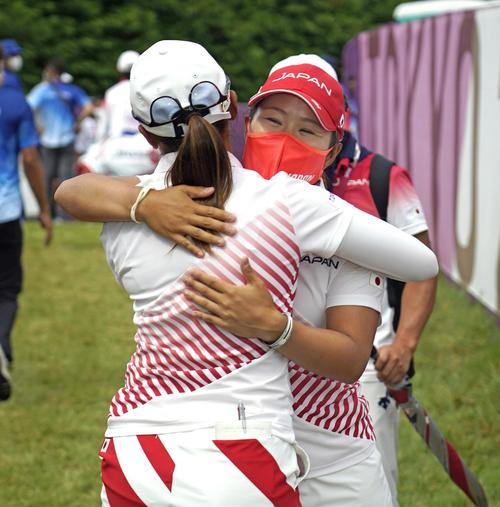 女子ゴルフで、銀メダルを懸けたプレーオフを制した稲見萌寧（手前）と抱き合う畑岡奈紗（共同）