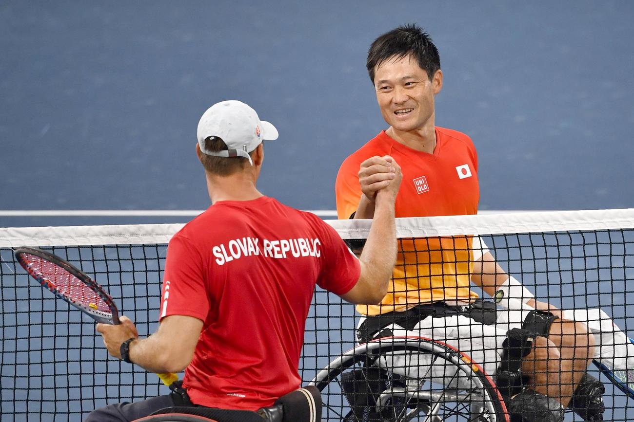 男子シングルス2回戦に勝利し、スロバキア選手（手前）と健闘をたたえ合う国枝慎吾＝有明テニスの森公園（共同）