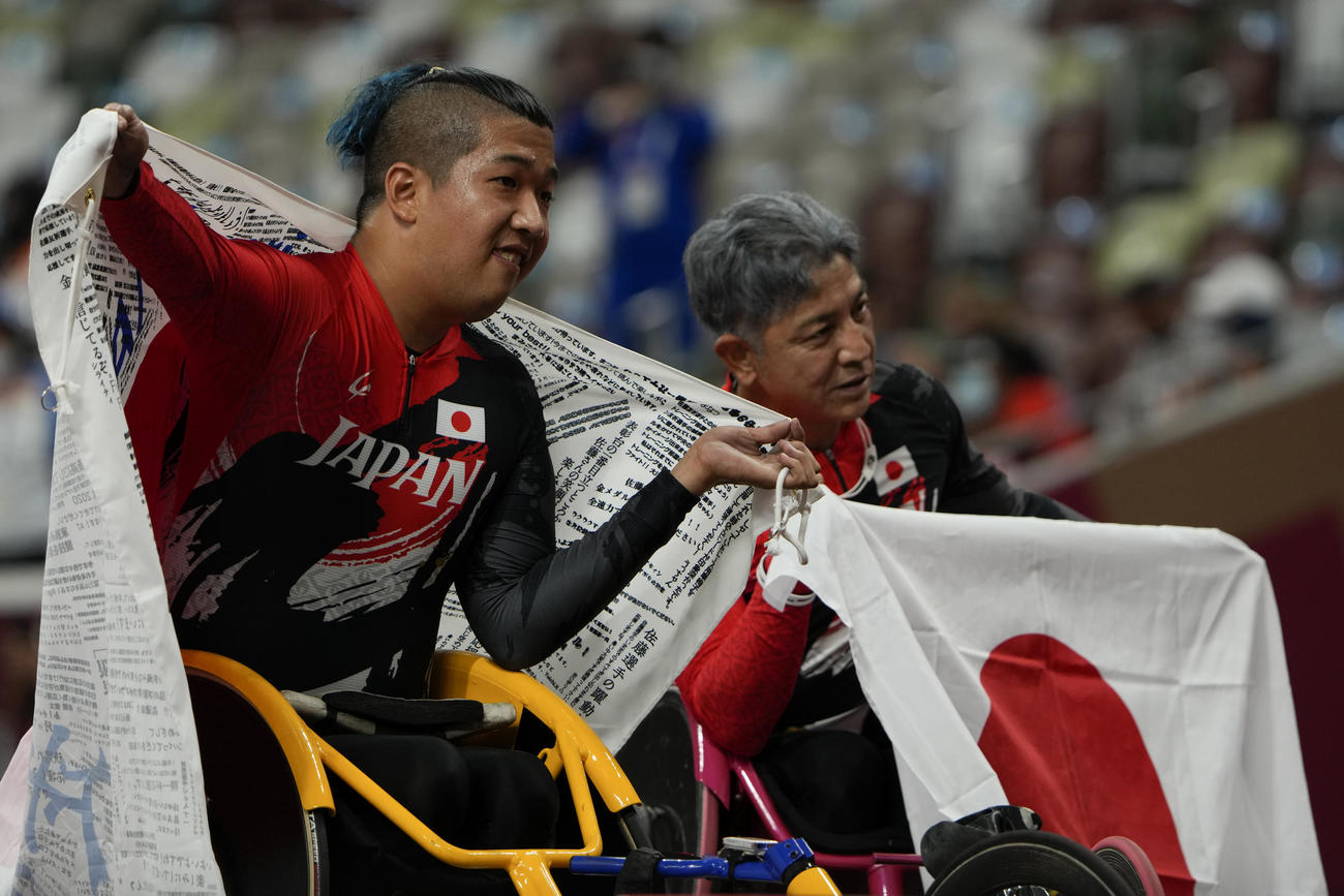 男子1500 メートル （車いすT52）優勝し日の丸を掲げる佐藤友祈（左）（AP）