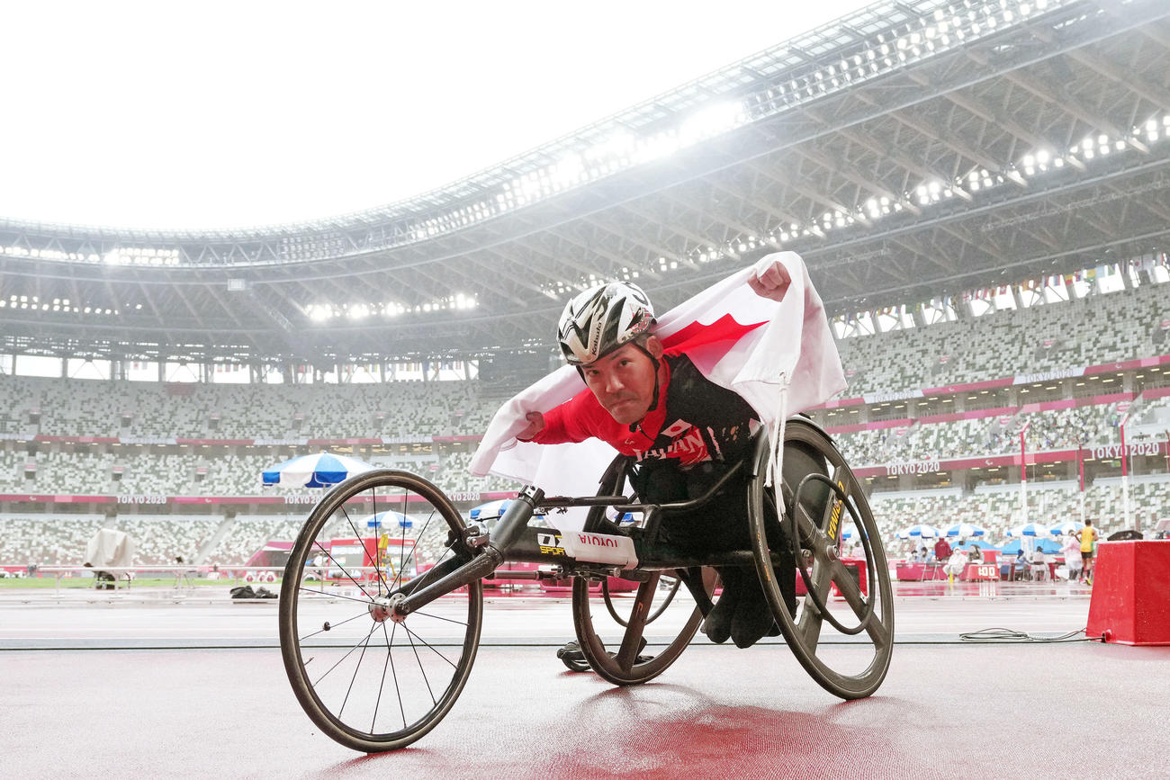 男子100メートル決勝で銀メダルを決めた大矢は日の丸を背にポーズを決める（撮影・滝沢徹郎）