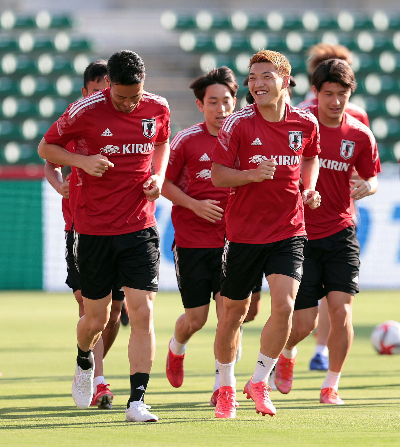 吉田（手前左）と言葉を交わしながら笑顔でランニングする堂安（同右）（撮影・前田充）