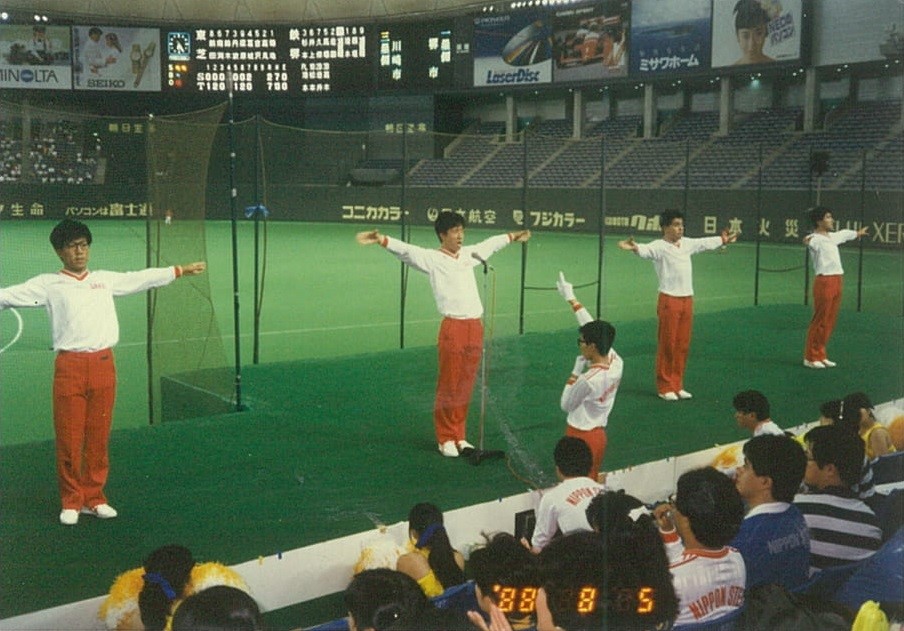 88年都市対抗野球準々決勝で野茂が先発登板した新日鉄堺を谷の父信賢さん（中央）はマイクスタンド前で応援。試合は3－7で敗れた（家族提供）