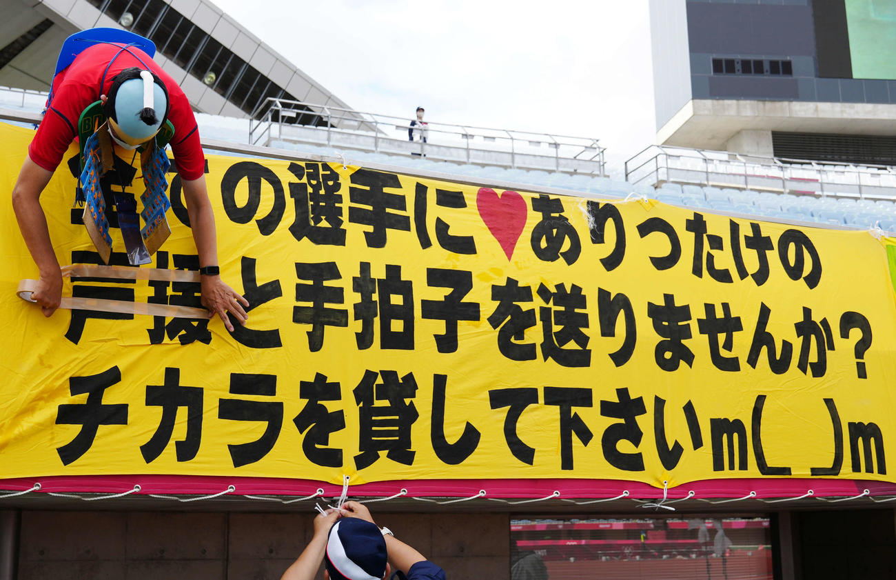 サッカー女子1次リーグの試合が行われるキューアンドエースタジアムみやぎで、横断幕が掲げられ、「声援」の文字をテープで隠す観客（撮影・江口和貴）