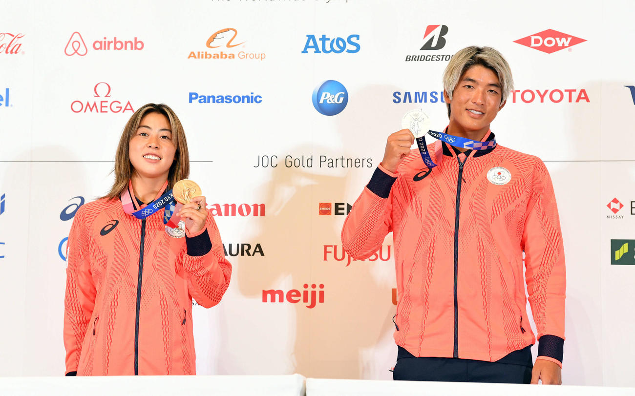 一夜明け会見を終え記念撮影する女子サーフィンの都筑（左）と男子サーフィンの五十嵐（撮影・滝沢徹郎）
