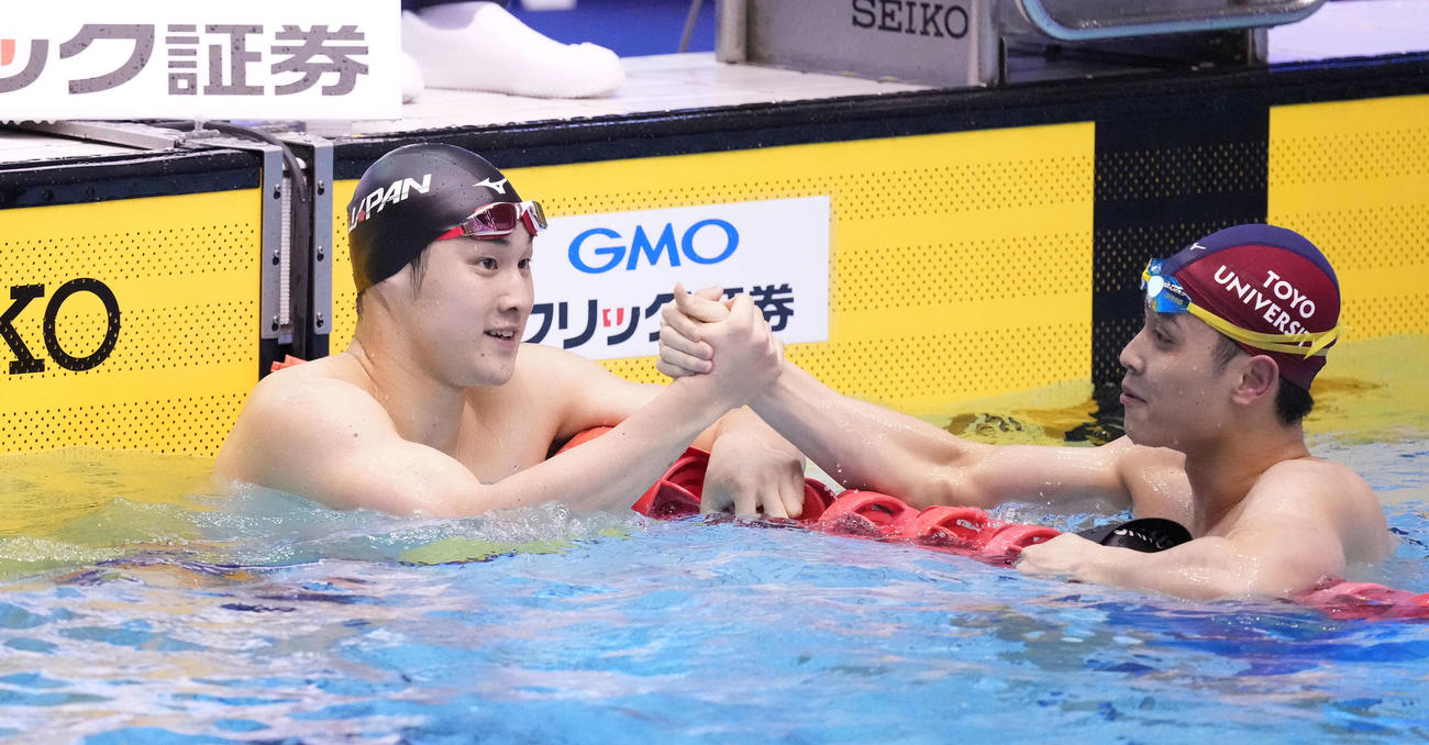 男子100メートル平泳ぎで優勝した佐藤（左）は2位花車とタッチを交わす（撮影・鈴木みどり）