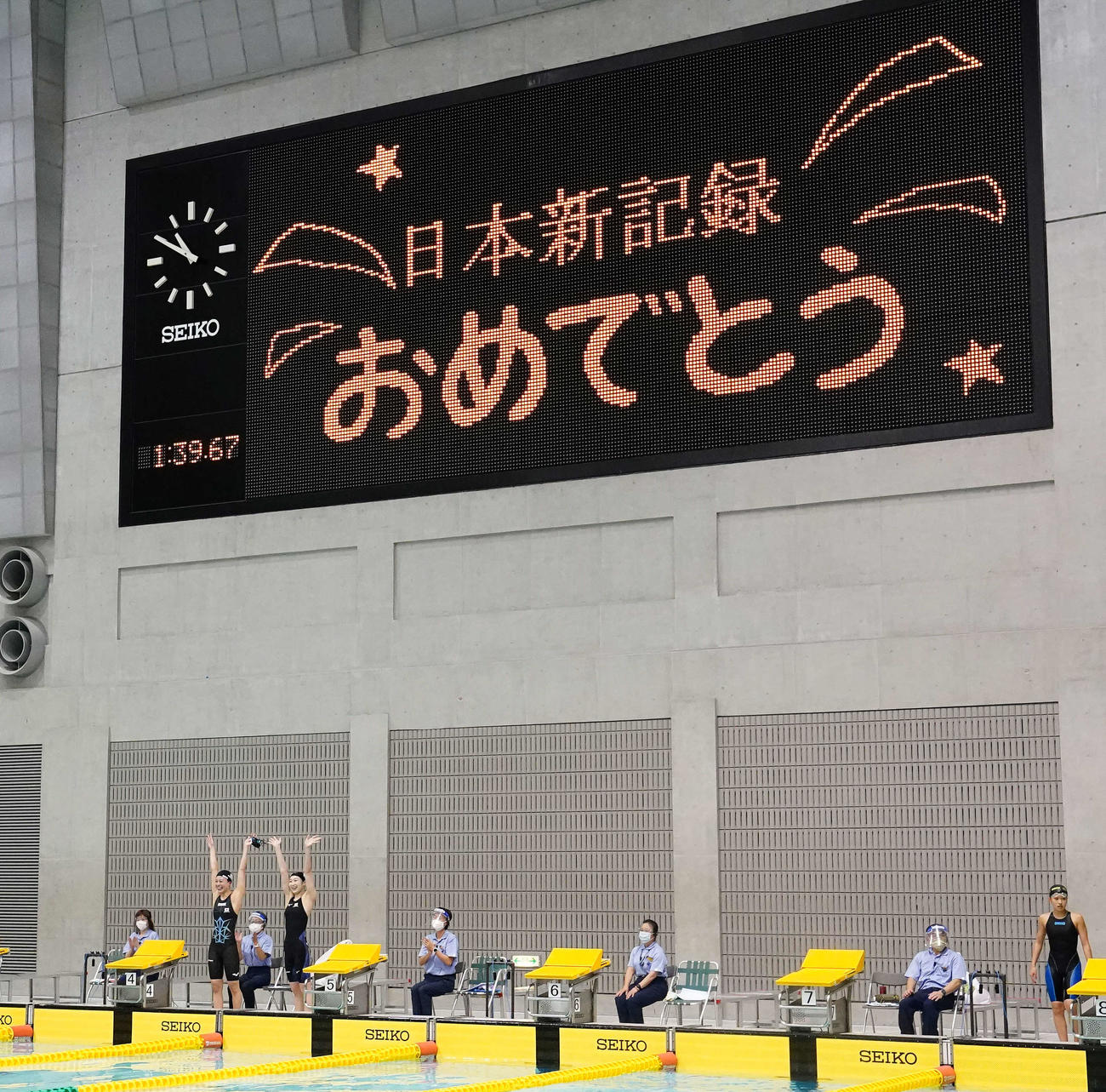 女子200メートルリレーで日本新記録を樹立し、アナウンスに手を上げ応える池江（手前右）と大本（撮影・江口和貴）