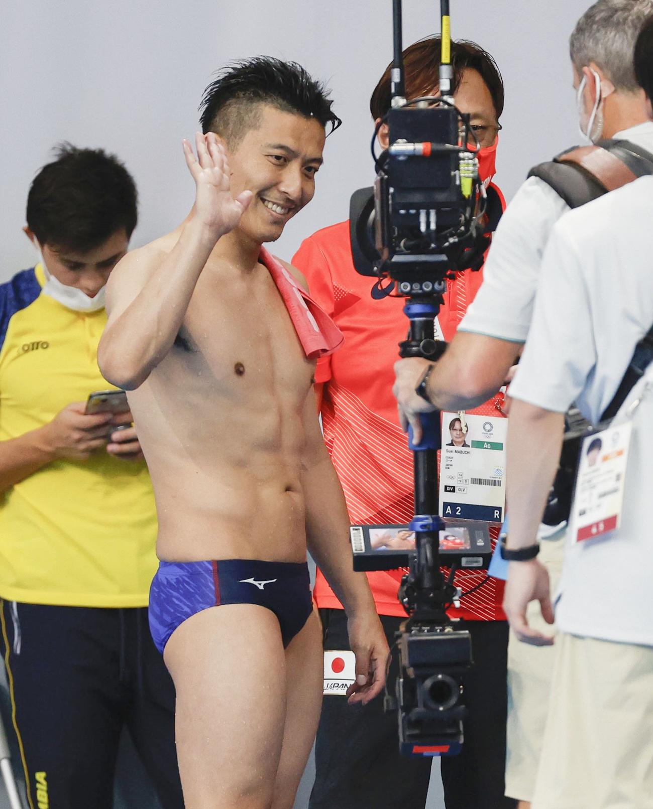 男子板飛び込み予選の最終演技を終え、中継カメラに笑顔で手を振る寺内健（共同）