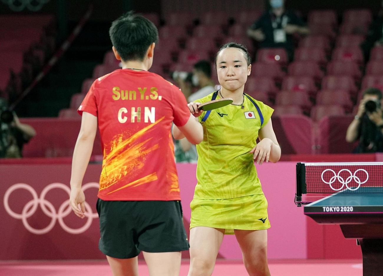 女子シングルス準決勝で中国の孫穎莎（左）に敗れ、ラケットでタッチを交わす伊藤美誠（共同）