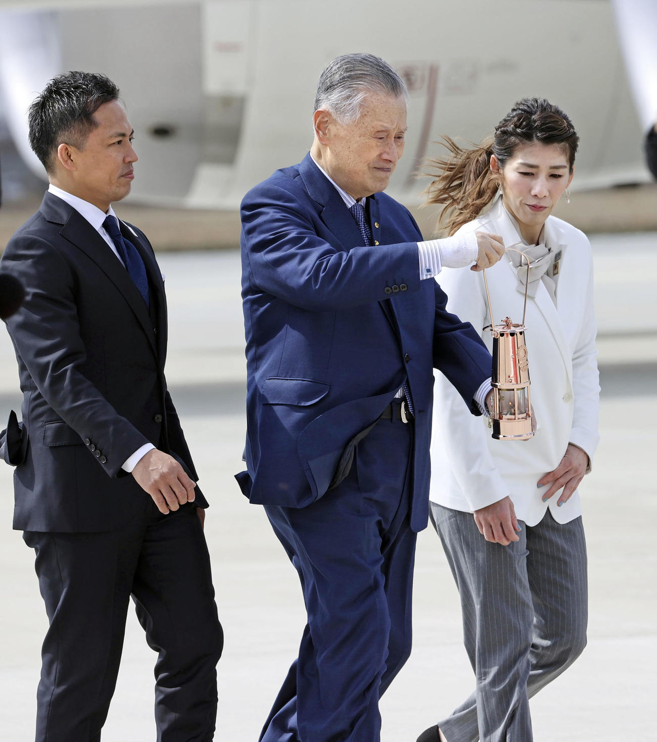 特別輸送機で到着した東京五輪の聖火を運ぶ組織委の森喜朗会長（中央）。左は柔道男子の野村忠宏さん、右はレスリング女子の吉田沙保里さん（共同）