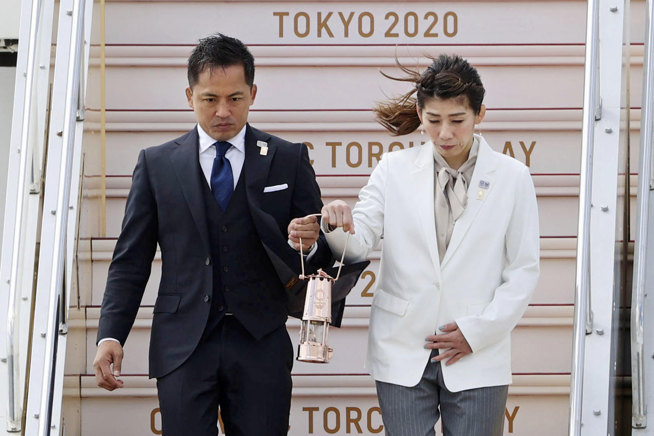 特別輸送機で到着した東京五輪の聖火を手にタラップを下りる柔道男子の野村忠宏さん（左）とレスリング女子の吉田沙保里さん（共同）