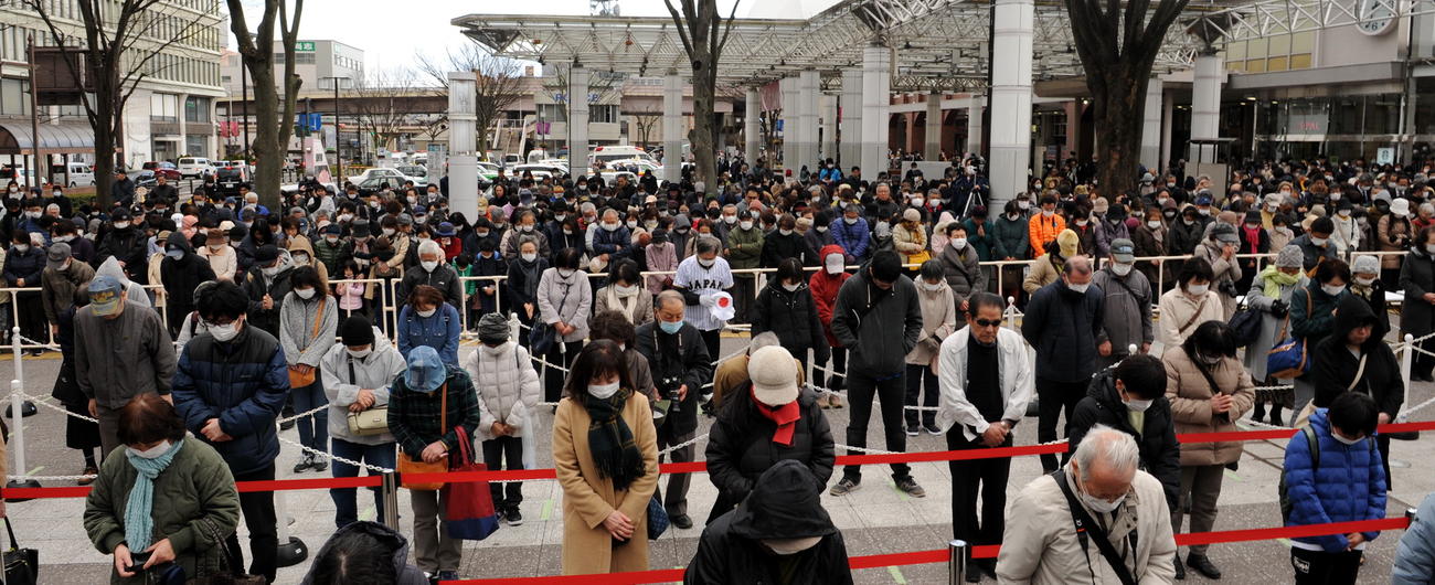 JR福島駅東口駅前広場で行われた復興の火の式典で展示公開前に黙とうする人々