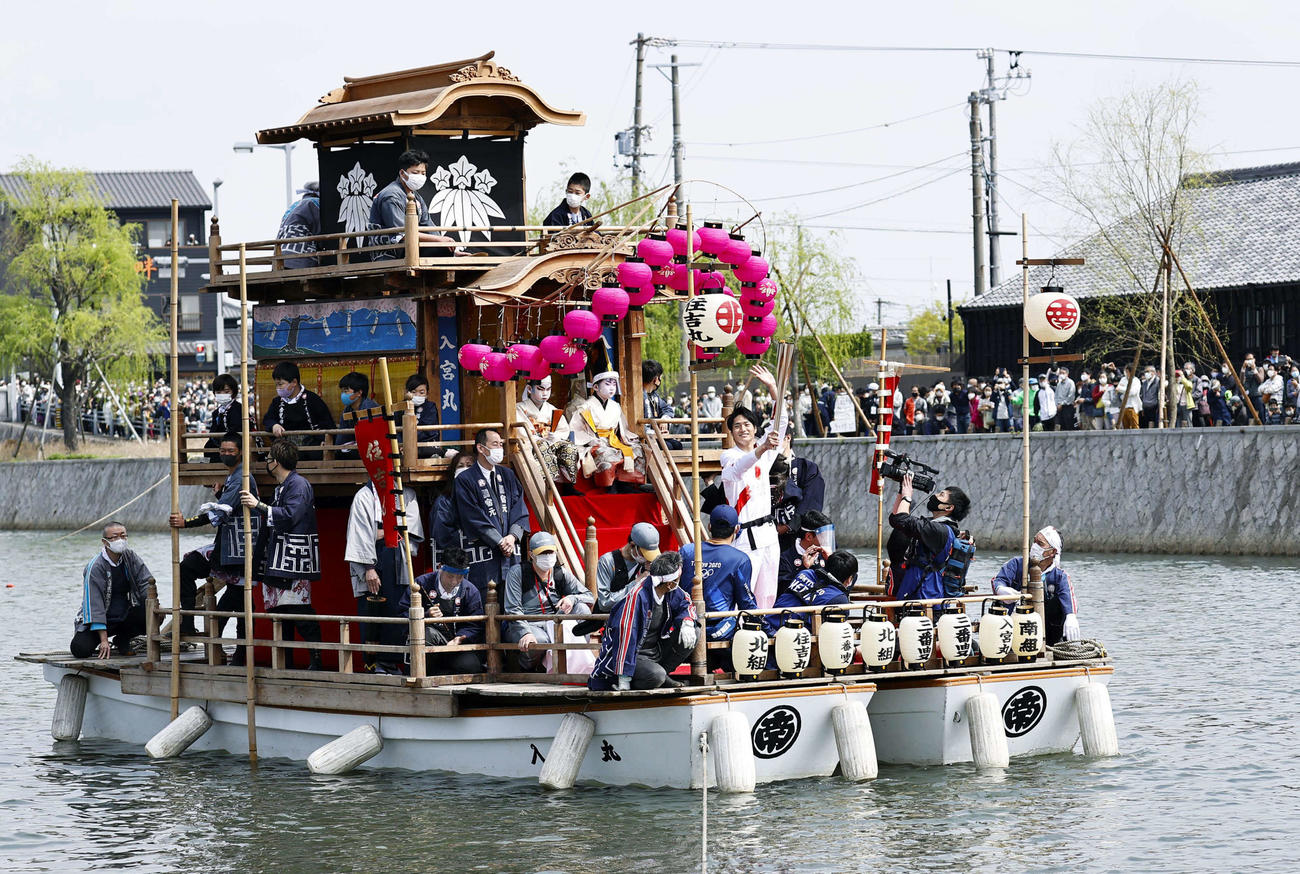 愛知県半田市の運河で聖火を運ぶ「ちんとろ舟」。先頭でトーチを掲げるのは平野泰新さん（共同）