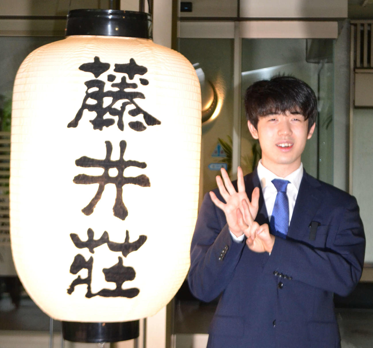 藤井荘のちょうちんの横で史上最年少7冠の「7」を表現する藤井聡太名人