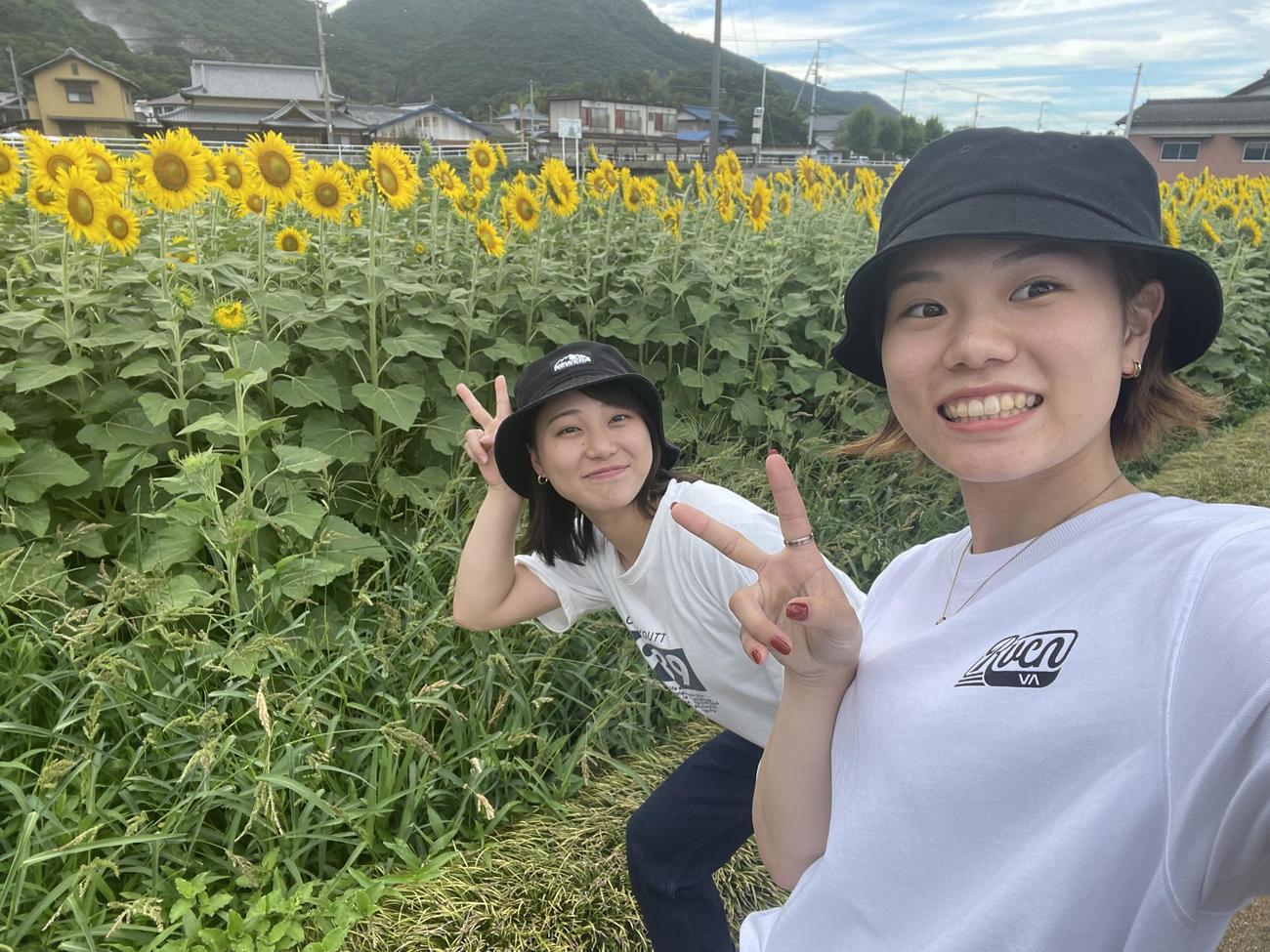 128期の藤原早菜（右）とひまわり畑（本人提供）