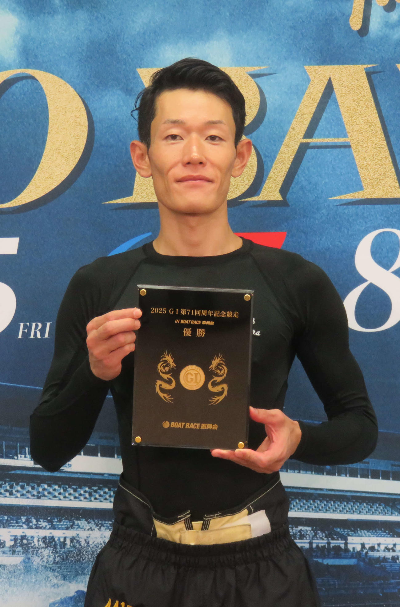 純金コインのはめ込まれた優勝盾を持つ茅原悠紀