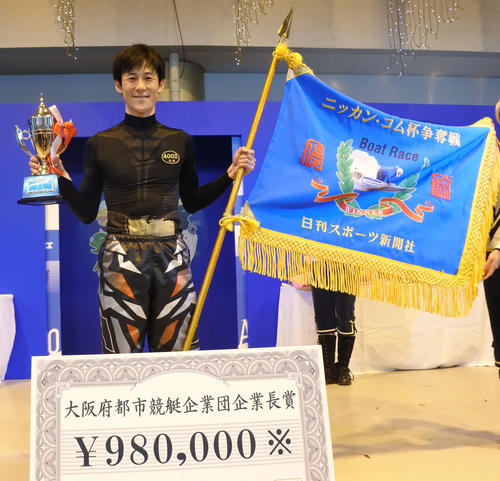 優勝旗、優勝カップを手に笑顔を浮かべる古結宏