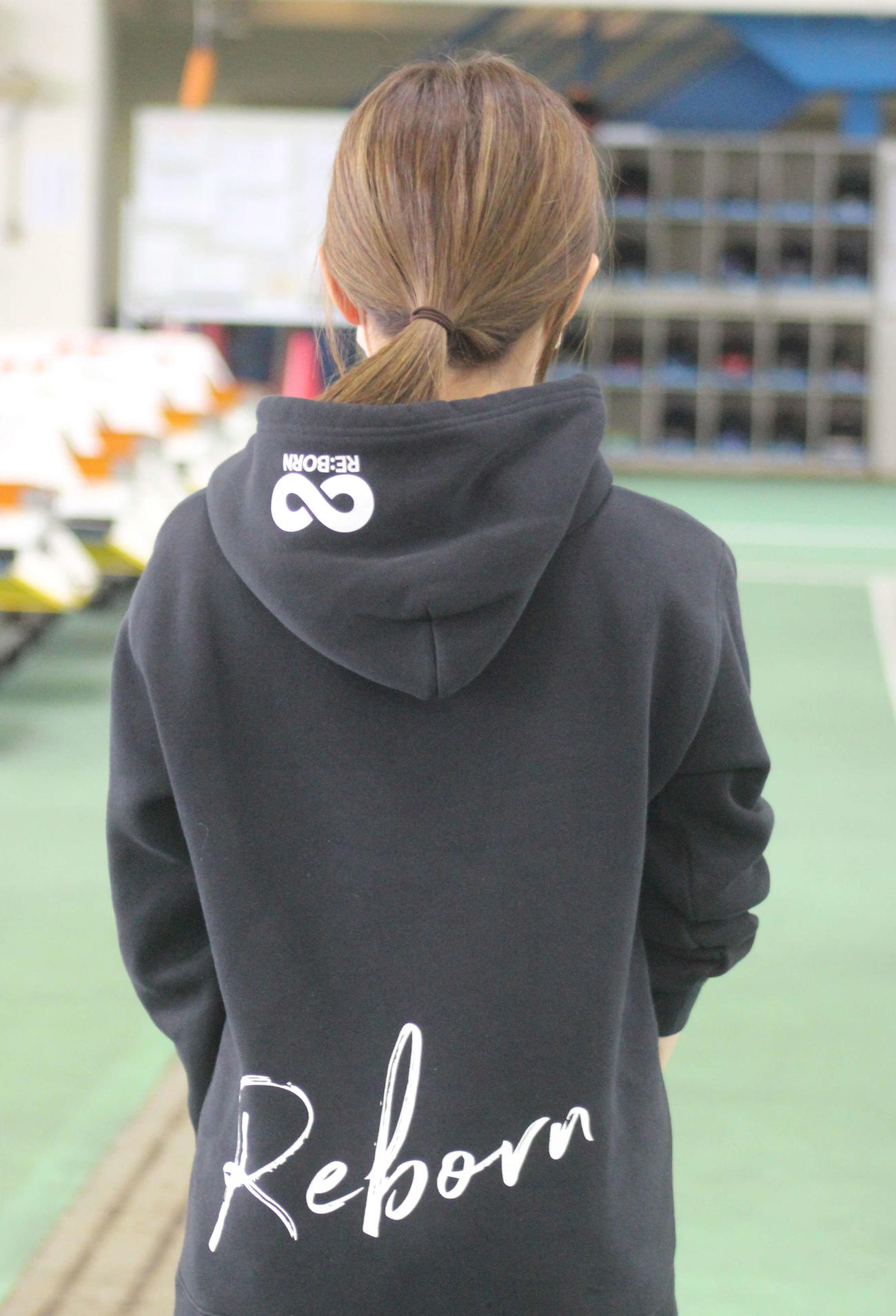 出口舞有子のパーカーの背中には「Reborn」の文字