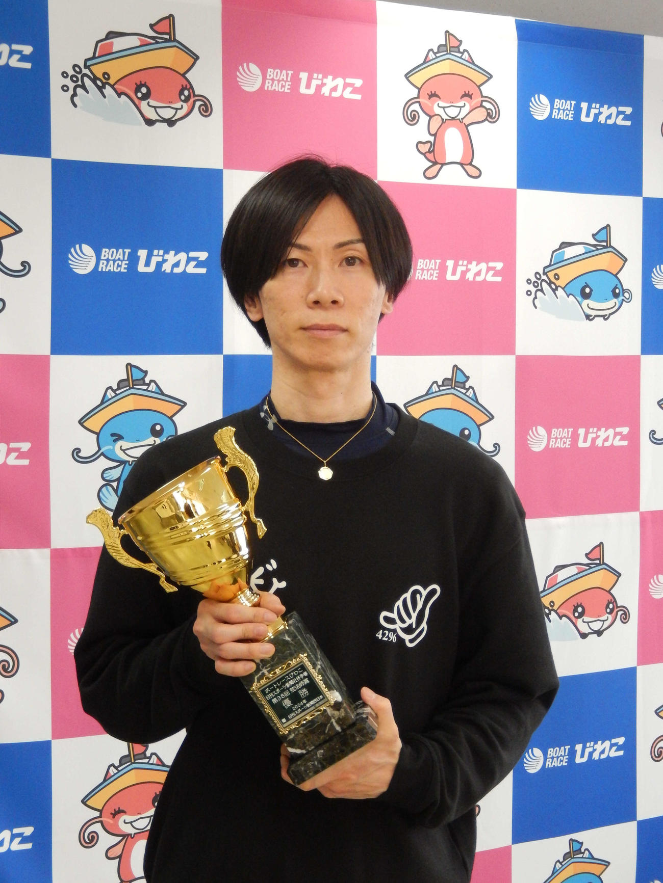優勝した岡崎恭裕が記念トロフィーを手に笑顔