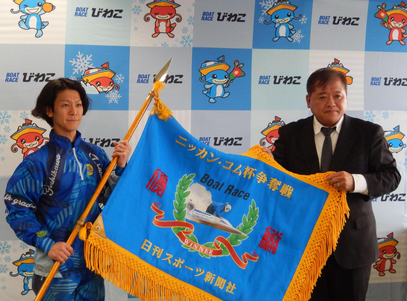 優勝の吉川貴仁(左）が、優勝旗を手にした。右は津波謙次日刊スポーツNEWSメディア事業本部公営戦略部部長