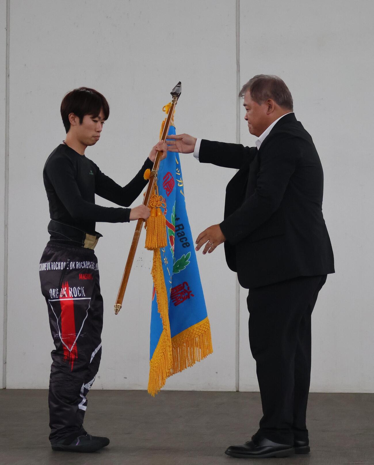 井本昌也が今年初V。公営戦略部の津波謙次部長から優勝旗が手渡された（撮影・北條直治）