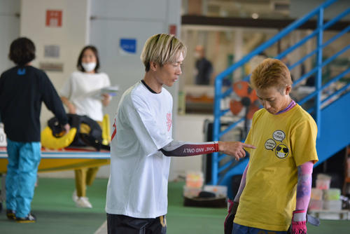 福岡周年のピットで峰竜太（左）が深谷知博のファッションチェック？